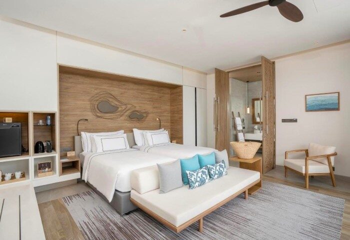 Melia Phuket Mai Khao beachfront gay luxury hotel room. Two beds with blue pillows, daybed, and bathroom access. Upscale gay travel.