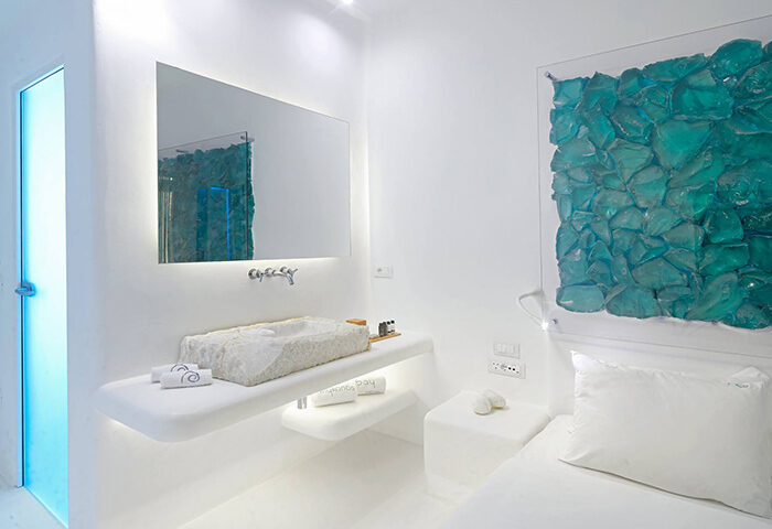 Mykonos Bay Resort villa bathroom. Stone sink, blue glass art. Beachfront villas near Mykonos Town gayborhood for big groups.