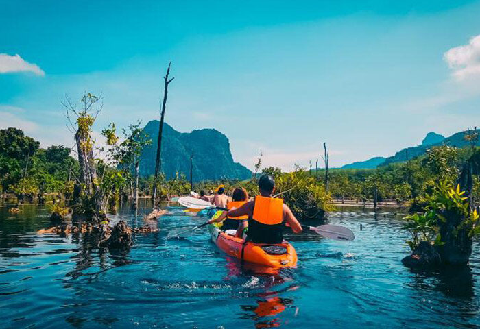 Gay travelers kayaking near Ao Nang Beach. Budget hostel tour leader guides through scenic Thailand landscape. Outdoor adventure.