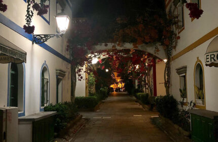 Street view near Paso Chico Gay Hotel, Gran Canaria. Budget gay hotel near Yumbo Center with bougainvillea and street light at night.