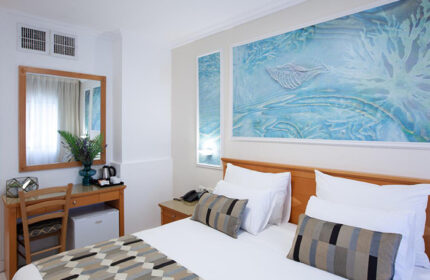 Armon Hayarkon Hotel room in Tel Aviv near Hilton Beach. Budget gay hotel room with bed, desk, and sea-themed artwork. Best gay travel choice.