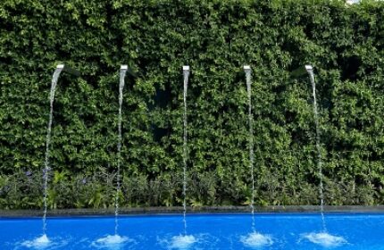 Ibis Styles Bangkok Silom rooftop pool. Best budget gay hotels in Bangkok. Water feature with greenery and city buildings in background.