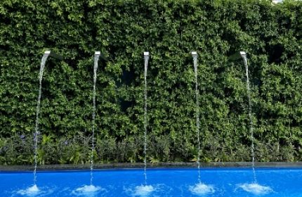 Ibis Styles Bangkok Silom rooftop pool. Best budget gay hotels in Bangkok. Water feature with greenery and city buildings in background.