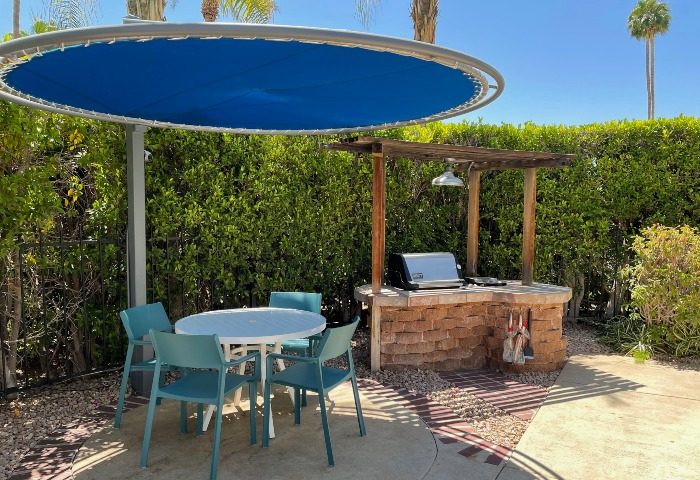 Desert Paradise Resort hotel patio with BBQ grill, table, and chairs. Best budget gay men hotel in Palm Springs for a relaxing vacation.