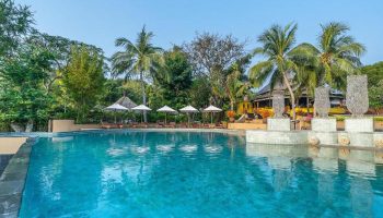 Paradee Resort pool view. Luxury beachfront villas in Koh Samet, Thailand. Gay-friendly hotel with pool, palm trees, and lounge chairs.
