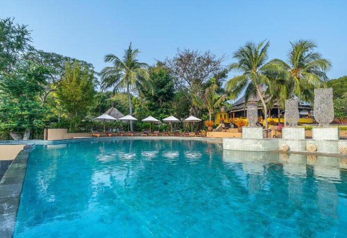 Paradee Resort pool view. Luxury beachfront villas in Koh Samet, Thailand. Gay-friendly hotel with pool, palm trees, and lounge chairs.