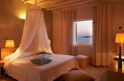 Upscale room at Porto Mykonos Hotel, a gay-friendly hotel in Mykonos Town. Bed with canopy, sea view. Best cheap price for gay travel.