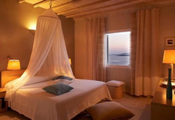 Upscale room at Porto Mykonos Hotel, a gay-friendly hotel in Mykonos Town. Bed with canopy, sea view. Best cheap price for gay travel.