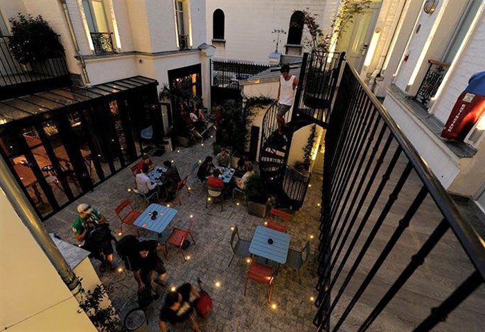 The 3 Ducks Eiffel Tower by Hiphophostels, a cheap, gay-friendly hostel near Paris gay bars. Courtyard view with guests at tables.