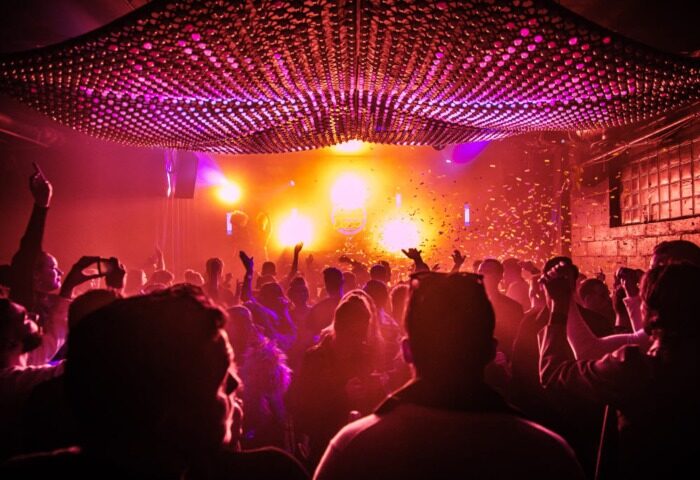 Inside Colours Hoxton, a gay bar in Shoreditch, London. People dance under vibrant lights and confetti at this popular cocktail bar.