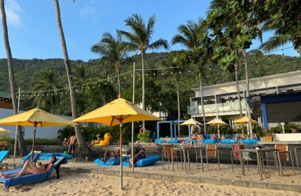 Explorar Koh Phangan Adults Only Resort beach view. Best gay hotels in Koh Phangan, Thailand. Beachfront lounge, palm trees, sunny day.