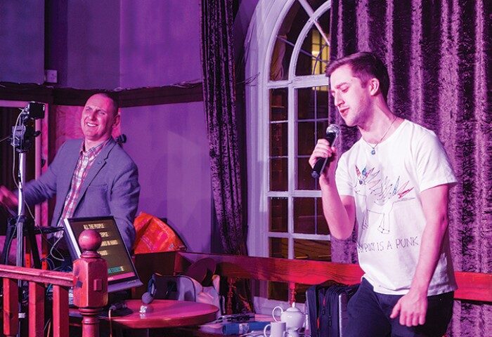 Central Station, best gay bar London: Karaoke night in King's Cross. Man singing into a microphone, another operating the karaoke machine.