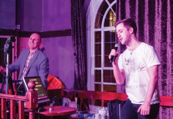 Central Station, best gay bar London: Karaoke night in King's Cross. Man singing into a microphone, another operating the karaoke machine.