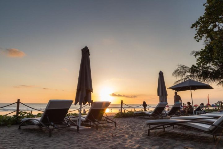 Double-Six Luxury Hotel Seminyak beachfront sunset view. Best gay honeymoon hotels in Bali. Beach chairs, umbrellas, and ocean vistas.