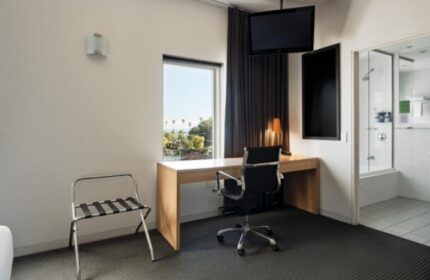 Saint Kilda Beach Hotel room interior. Desk, chair, and TV. Bathroom visible. Best gay beachfront hotels near gay bars in Melbourne.