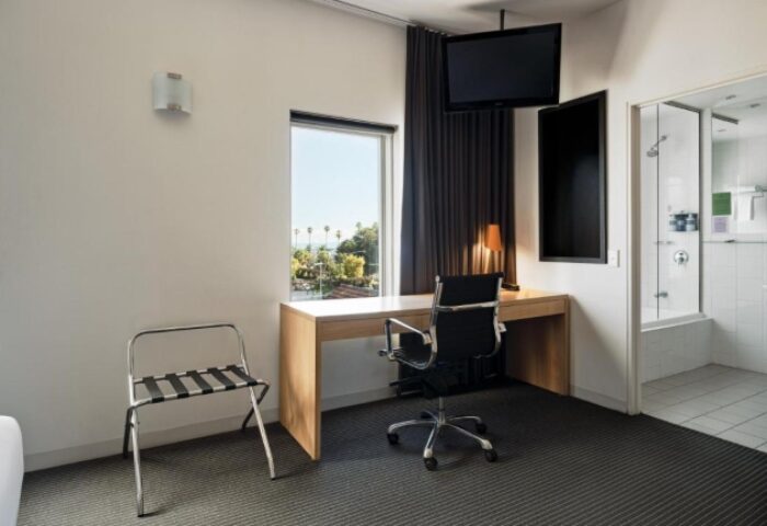 Saint Kilda Beach Hotel room interior. Desk, chair, and TV. Bathroom visible. Best gay beachfront hotels near gay bars in Melbourne.