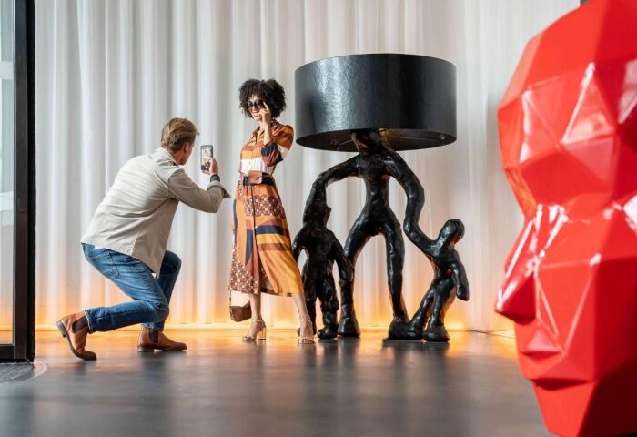 art'otel Amsterdam: Man taking photo of woman by artful lamp. Best gay-friendly hotel with young cool gay crowd. Modern interior design.