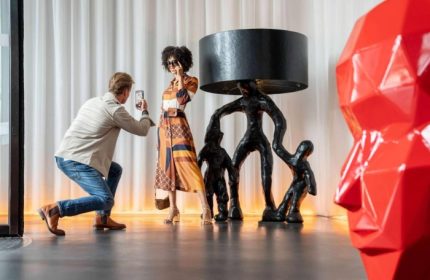 art'otel Amsterdam: Man taking photo of woman by artful lamp. Best gay-friendly hotel with young cool gay crowd. Modern interior design.