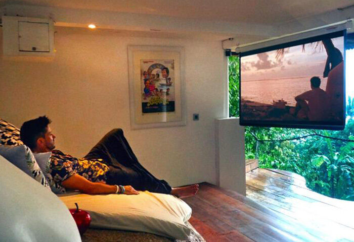 Gay-friendly hotel, Somewhere Only We Know, Koh Phangan. Man relaxing in beachfront room watching TV. Tropical gay travel advice.
