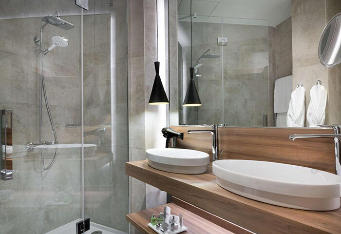 NH Collection Madrid Gran Via hotel bathroom. Modern design with double sinks, shower, and pendant lights. Gay-friendly hotel in Madrid.