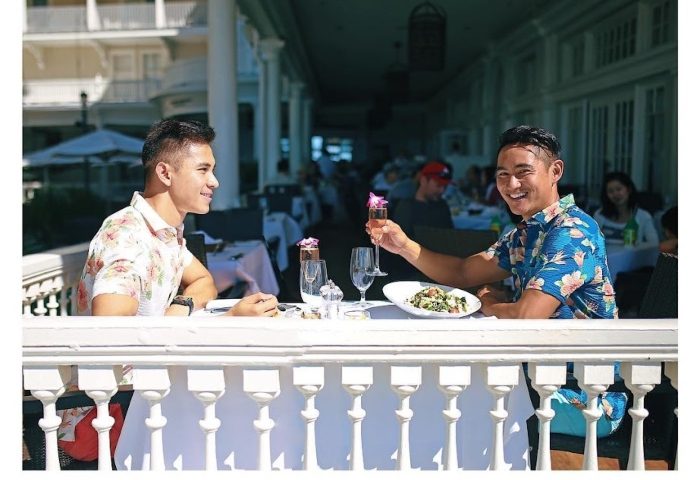 Gay couple celebrates their honeymoon at Moana Surfrider, A Westin Resort & Spa, Waikiki Beach, Hawaii. Beachfront dining.
