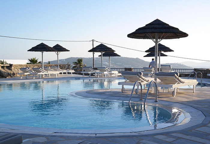 Hermes Mykonos Hotel pool view. Best gay honeymoon hotel in Mykonos Town gayborhood, Greece. Luxury travel for gay men. Sunbeds & umbrellas.
