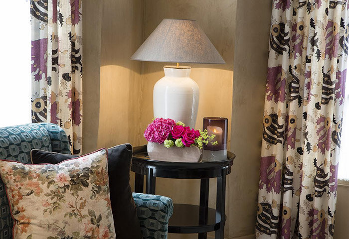 Les Tournelles hotel interior, best gay honeymoon hotel in Paris' gayborhood Marais. Lamp, flowers, curtains, pillows, table.