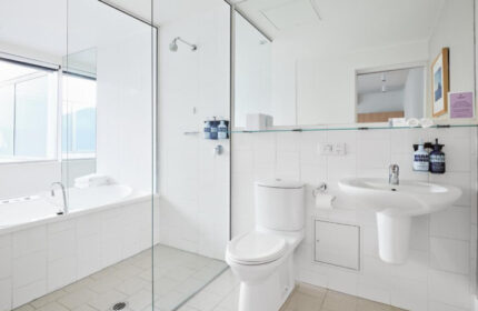 Saint Kilda Beach Hotel, Melbourne, gay honeymoon destination. White bathroom with tub, toilet, and sink. Modern design, ideal for gay couples.