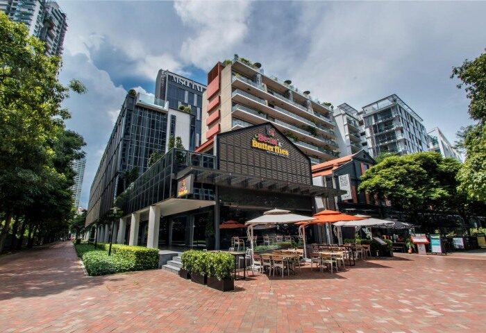 M Social Singapore, a top gay honeymoon hotel. Exterior view of the hotel, showcasing its modern architecture and outdoor dining area.