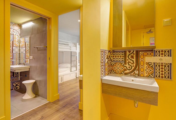 Generator Barcelona's best gay hostel private bed and bathroom. Interior view of a vibrant, yellow-themed room with bunk beds and a stylish bathroom.