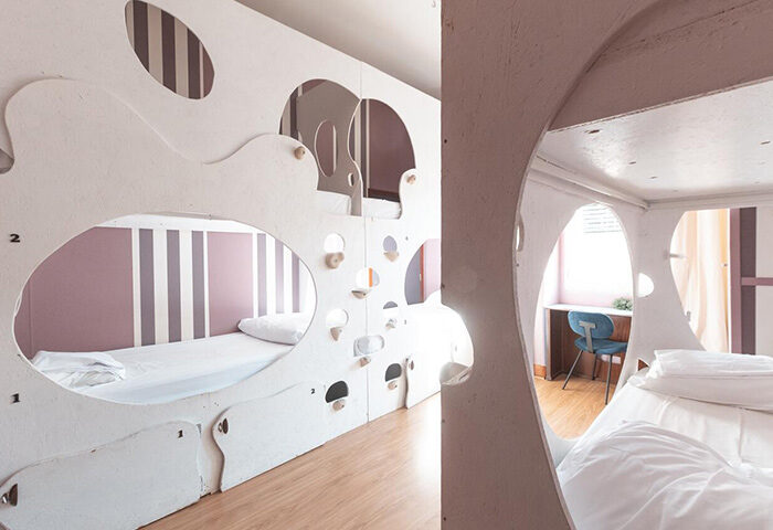 Sunset Destination Hostel Lisbon bunk beds. Modern design, white structures, purple striped walls. Best hostel for solo gay travelers.