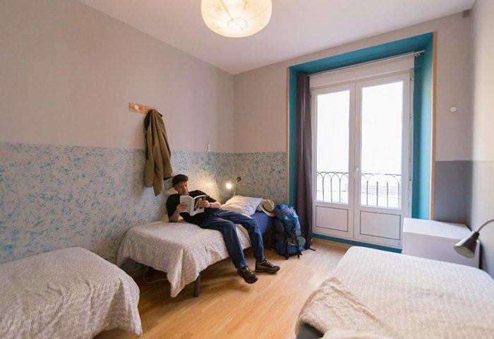 Sungate One, best gay hostel Madrid. Man reading in a room, a place for gay travellers to meet. Budget travel, shared accommodation.