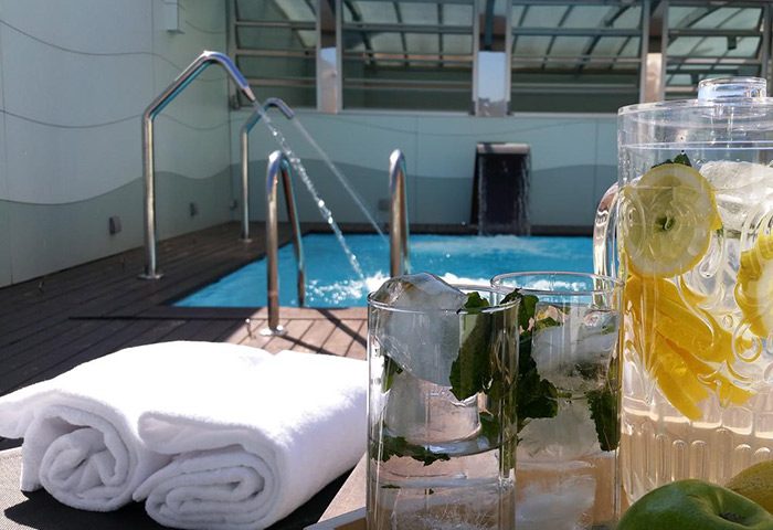 Ako Suites Hotel rooftop pool scene. Refreshments, towels, and a pool with water feature. Best gay hotel Barcelona serviced apartment.