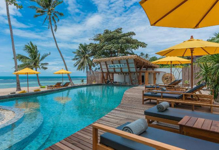 Princess Paradise Koh Phangan beachfront swimming pool. Gay hotel with sun loungers, umbrellas, and palm trees. Tropical paradise.