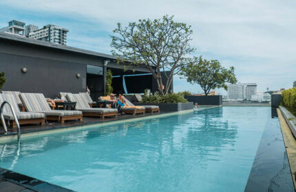 Page 10 Hotel rooftop pool in Pattaya City. Gay hotel near gay bars and saunas. People relaxing on lounge chairs by the pool.