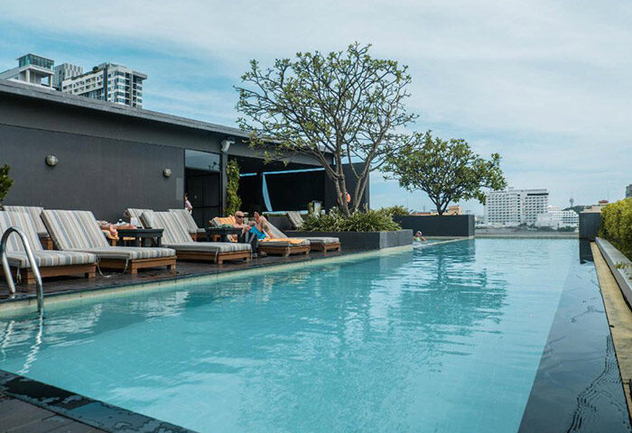Page 10 Hotel rooftop pool in Pattaya City. Gay hotel near gay bars and saunas. People relaxing on lounge chairs by the pool.