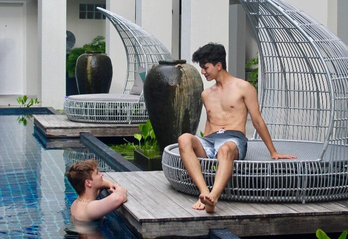 Gay honeymoon at Outrigger Surin Beach Resort, Phuket, Thailand. Two shirtless men relaxing by the pool in a luxury gay-friendly hotel.