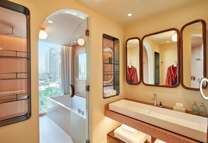 Bathroom at The Standard, Bangkok Mahanakhon, a top gay-friendly hotel. Features modern design, bathtub with city view, & stylish mirrors.