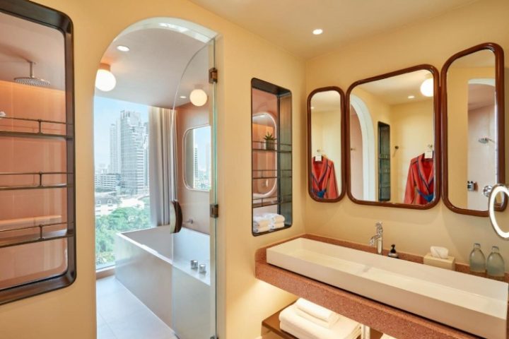Bathroom at The Standard, Bangkok Mahanakhon, a top gay-friendly hotel. Features modern design, bathtub with city view, & stylish mirrors.