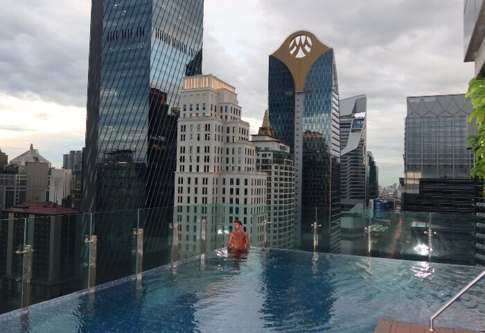 Gay man at Hotel Indigo Bangkok Wireless Road's infinity pool. Best gay hotels Bangkok offer stunning city views. #gaytravel