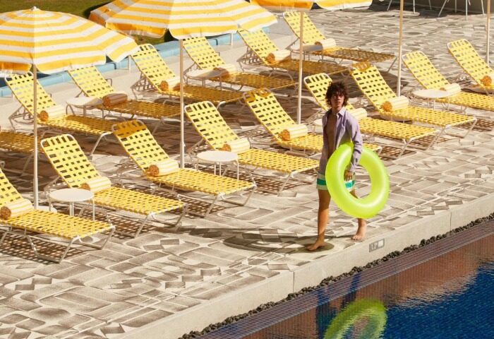 The Standard, Hua Hin: A man with a floatie at the gay-friendly hotel pool. Yellow striped umbrellas and lounge chairs line the pool at this beach resort.