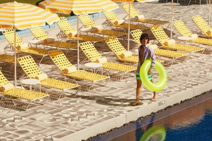 The Standard, Hua Hin: A man with a floatie at the gay-friendly hotel pool. Yellow striped umbrellas and lounge chairs line the pool at this beach resort.