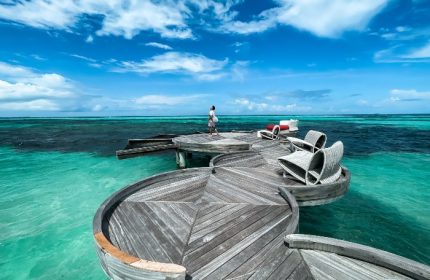 LUX* South Ari Atoll, Maldives water villas. Man on a wooden deck above turquoise water. Best gay hotels offer luxury and privacy.
