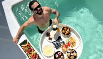 Gay man enjoying breakfast in a pool at Akkadian Gay Only Hotel, Mykonos. Best gay hotels on Instagram. Gay travel.