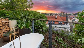 Mosaic House Design Hotel's private balcony with bathtub. Best gay hotels Prague Old Town view at sunset. Gay travel luxury.