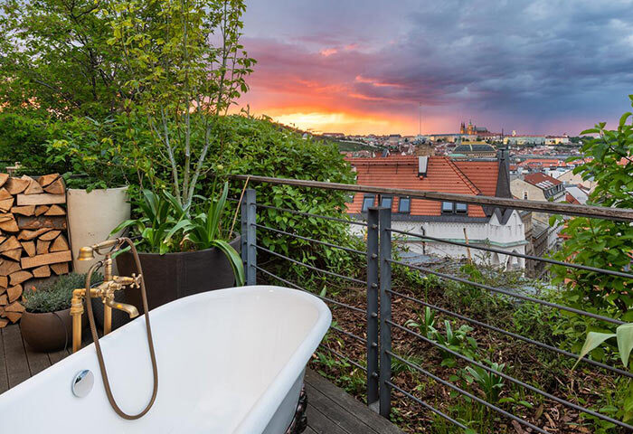 Mosaic House Design Hotel's private balcony with bathtub. Best gay hotels Prague Old Town view at sunset. Gay travel luxury.