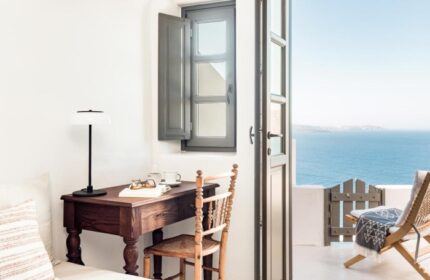 Armenaki Santorini room with sea view. Best gay hotels near gay beach. Desk, chair, open door to balcony. Gay travel in Santorini, Greece.