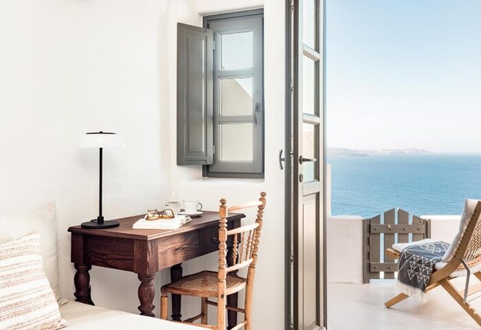 Armenaki Santorini room with sea view. Best gay hotels near gay beach. Desk, chair, open door to balcony. Gay travel in Santorini, Greece.