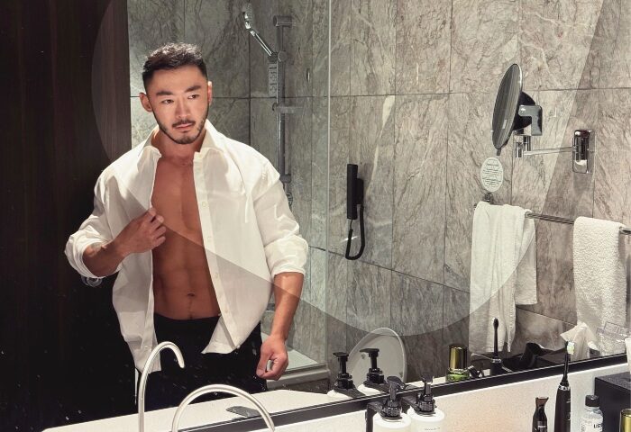 Gay-friendly voco Orchard Singapore hotel bathroom. Man in unbuttoned shirt, abs visible. Best gay hotels in Singapore City Centre for gay men.