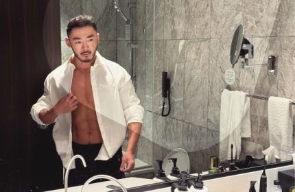 Gay-friendly voco Orchard Singapore hotel bathroom. Man in unbuttoned shirt, abs visible. Best gay hotels in Singapore City Centre for gay men.